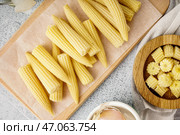 Деревянная доска с вкусными консервированными кукурузными початками на светлом фоне. Стоковое фото, фотограф Pixel_shot / Фотобанк Лори