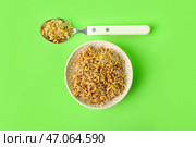 Чашка и ложка с пророщенной пшеницей на светло-зеленом фоне. Стоковое фото, фотограф Pixel_shot / Фотобанк Лори