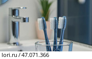 Toothbrushes in a cup on white countertop in bathroom background. Family toothbrushes in ceramic holder. Tooth brushes in mug. Oral care, wellness, dental hygiene, fresh breath. Toiletries Still Life. Стоковое AI-видео, аниматор Марина Демидюк / Фотобанк Лори