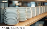 Stacked white bowls neatly arranged on wooden shelf in a modern kitchen setting. Стопка белых тарелок, аккуратно расставленных на деревянной полке в современной кухне. Стоковое AI-изображение, AI-художник Katsiaryna Repich / Фотобанк Лори