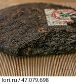 Aged Puerh Tea Cake on a Bamboo Mat, highlighting its rich heritage and craftsmanship. Стоковое фото, фотограф David Kashakhi / Фотобанк Лори