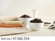 Миски с кофейным скрабом для тела, кофейными зернами и массажной щеткой для тела на светлом фоне с налетом времени. Стоковое фото, фотограф Pixel_shot / Фотобанк Лори