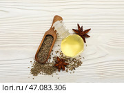 Бутылка с эфирным маслом с анисовыми звездами, сухими семенами и ложкой на белом деревянном фоне. Стоковое фото, фотограф Pixel_shot / Фотобанк Лори