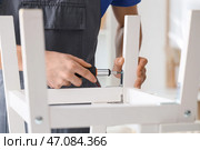 Мужчина-плотник затягивает винт в белой деревянной мебели с помощью отвертки, крупный план. Стоковое фото, фотограф Pixel_shot / Фотобанк Лори