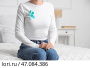 Молодая женщина с бирюзовой лентой сидит в спальне. Месяц повышения осведомленности о здоровье шейки матки. Стоковое фото, фотограф Pixel_shot / Фотобанк Лори
