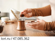 Женские руки наполняют турку молотым кофе на столе на кухне. Стоковое фото, фотограф Pixel_shot / Фотобанк Лори