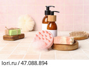Массажер для кожи головы с шампунями и бутылками косметических продуктов на розовом плиточном фоне. Стоковое фото, фотограф Pixel_shot / Фотобанк Лори
