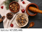 Миски с традиционной украинской кутьей, ветка ели и рождественские шары на черном деревянном фоне. Стоковое фото, фотограф Pixel_shot / Фотобанк Лори