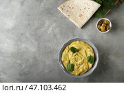 Тарелка с вкусным хумусом и лепешкой на сером столе. Стоковое фото, фотограф Pixel_shot / Фотобанк Лори