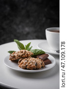 Тарелка с вкусным овсяным печеньем и шоколадом на белом столе на темном фоне. Стоковое фото, фотограф Pixel_shot / Фотобанк Лори