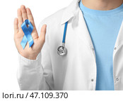 Доктор держа голубую ленту на белой предпосылке, крупном плане. Концепция рака простаты. Стоковое фото, фотограф Pixel_shot / Фотобанк Лори