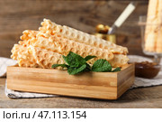 Доска с вкусными вафельными трубочками и мятой на деревянном фоне. Стоковое фото, фотограф Pixel_shot / Фотобанк Лори