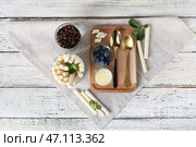 Стакан вкусных вафельных трубочек и доска со сгущенным молоком на белом деревянном фоне. Стоковое фото, фотограф Pixel_shot / Фотобанк Лори