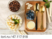 Стакан вкусных вафельных трубочек и доска со сгущенным молоком на белом деревянном фоне. Стоковое фото, фотограф Pixel_shot / Фотобанк Лори