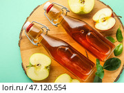 Доска со стеклянными бутылками свежего яблочного уксуса и фруктами на бирюзовом фоне. Стоковое фото, фотограф Pixel_shot / Фотобанк Лори