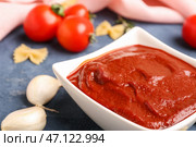 Чаша вкусной томатной пасты, зубчики чеснока и сырые макароны фарфалле на сером фоне гранж. Стоковое фото, фотограф Pixel_shot / Фотобанк Лори