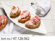 Тарелка с вкусными брускеттами из редьки на столе из белой плитки. Стоковое фото, фотограф Pixel_shot / Фотобанк Лори