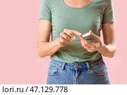 Зрелая диабетичка измеряет уровень сахара в крови с помощью глюкометра на розовом фоне, крупным планом. Стоковое фото, фотограф Pixel_shot / Фотобанк Лори