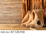 Ковбойские сапоги и лассо на деревянном фоне. Стоковое фото, фотограф Pixel_shot / Фотобанк Лори