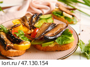 Тарелка вкусных бутербродов с консервированными копчеными шпротами на столе. Стоковое фото, фотограф Pixel_shot / Фотобанк Лори