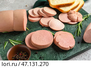 Сланцевая доска с вкусной нарезанной вареной колбасой на столе, крупным планом. Стоковое фото, фотограф Pixel_shot / Фотобанк Лори