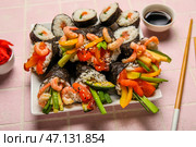 Тарелка с вкусными суши-конусами, роллами и соевым соусом на фоне цветной плитки, крупным планом. Стоковое фото, фотограф Pixel_shot / Фотобанк Лори
