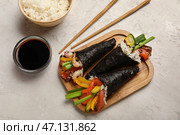 Деревянная доска с вкусными роллами суши, соевым соусом, вареным рисом и палочками для еды на светлом фоне. Стоковое фото, фотограф Pixel_shot / Фотобанк Лори