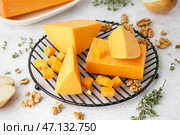 Охладительная решетка с кусочками вкусного чеддер-сыра на светлом фоне. Стоковое фото, фотограф Pixel_shot / Фотобанк Лори