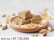 Деревянная тарелка с кусочками вкусной халвы и арахисом на белом фоне. Стоковое фото, фотограф Pixel_shot / Фотобанк Лори