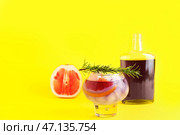 Стакан с фиолетовым джином и тоником с бутылкой, грейпфрутом и розмарином на желтом фоне. Стоковое фото, фотограф Pixel_shot / Фотобанк Лори