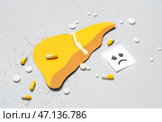 Желтая бумажная печень с унылым лицом и таблетки на сером фоне. Стоковое фото, фотограф Pixel_shot / Фотобанк Лори