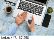 Женщина наносит антисептик на руки за синим столом в офисе. Стоковое фото, фотограф Pixel_shot / Фотобанк Лори