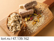 Деревянная доска из сладкой кунжутной халвы с фисташками на цветном фоне, крупным планом. Стоковое фото, фотограф Pixel_shot / Фотобанк Лори