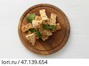 Деревянная доска с кусочками вкусных кунжутных козинаков на светлом деревянном фоне. Стоковое фото, фотограф Pixel_shot / Фотобанк Лори