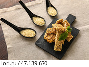 Доска с вкусными козинаками и ложками кунжута на столе. Стоковое фото, фотограф Pixel_shot / Фотобанк Лори