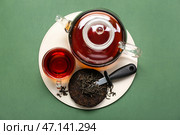 Сухой прессованный чай пуэр с ножом, стаканом и чайником на зеленом фоне. Стоковое фото, фотограф Pixel_shot / Фотобанк Лори