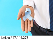 Человек с лентой осведомленности на синем фоне, крупным планом. Концепция рака простаты. Стоковое фото, фотограф Pixel_shot / Фотобанк Лори