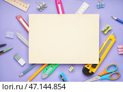 Чистый лист бумаги с универсальными ножами и канцелярскими принадлежностями на фиолетовом фоне. Стоковое фото, фотограф Pixel_shot / Фотобанк Лори