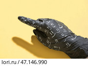 Рука в черной медицинской перчатке с рисунками улыбки, указывающими на что-то на цветном фоне, крупным планом. Стоковое фото, фотограф Pixel_shot / Фотобанк Лори