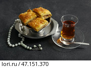 Вкусная турецкая пахлава с тасбихом и чаем на темном фоне. Стоковое фото, фотограф Pixel_shot / Фотобанк Лори