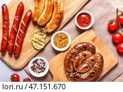 Деревянные доски со вкусными жареными колбасками и соусами на столе. Стоковое фото, фотограф Pixel_shot / Фотобанк Лори