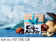 Вкусные восточные сладости с подарком и поздравительной открыткой для Ид аль-Фитр (Праздник разговения) на цветном фоне. Стоковое фото, фотограф Pixel_shot / Фотобанк Лори