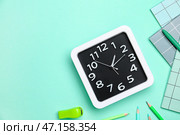 Стильные часы с канцелярскими принадлежностями на цветном фоне. Стоковое фото, фотограф Pixel_shot / Фотобанк Лори
