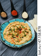 Тарелка с вкусным хумусом, питой и специями на фоне темного дерева. Стоковое фото, фотограф Pixel_shot / Фотобанк Лори