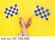 Женские руки с гоночными флагами на цветном фоне. Стоковое фото, фотограф Pixel_shot / Фотобанк Лори