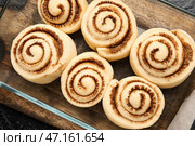 Форма для выпечки с сырыми булочками с корицей и на черном фоне, крупным планом. Стоковое фото, фотограф Pixel_shot / Фотобанк Лори