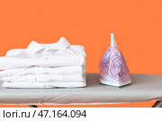 Доска с электрическим утюгом и чистой одеждой на цветном фоне, крупным планом. Стоковое фото, фотограф Pixel_shot / Фотобанк Лори