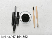 Чаша с зубным порошком с активированным углем, щетки и бамбуковые палочки на белом фоне. Стоковое фото, фотограф Pixel_shot / Фотобанк Лори