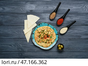 Тарелка с вкусным хумусом, питой и специями на фоне темного дерева. Стоковое фото, фотограф Pixel_shot / Фотобанк Лори