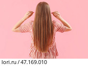 Молодая женщина с берушами на розовом фоне, вид сзади. Стоковое фото, фотограф Pixel_shot / Фотобанк Лори